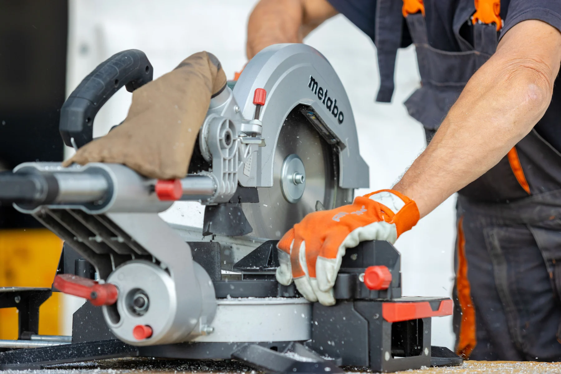 Gloved hands operating a mitre saw
