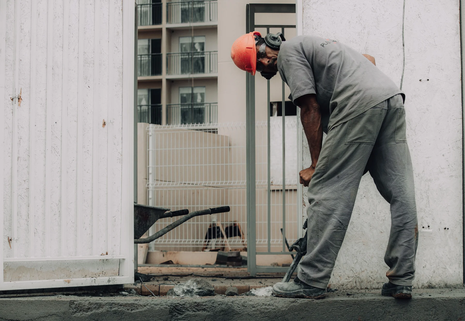 A worker wearing protective equipment using a jackhammer