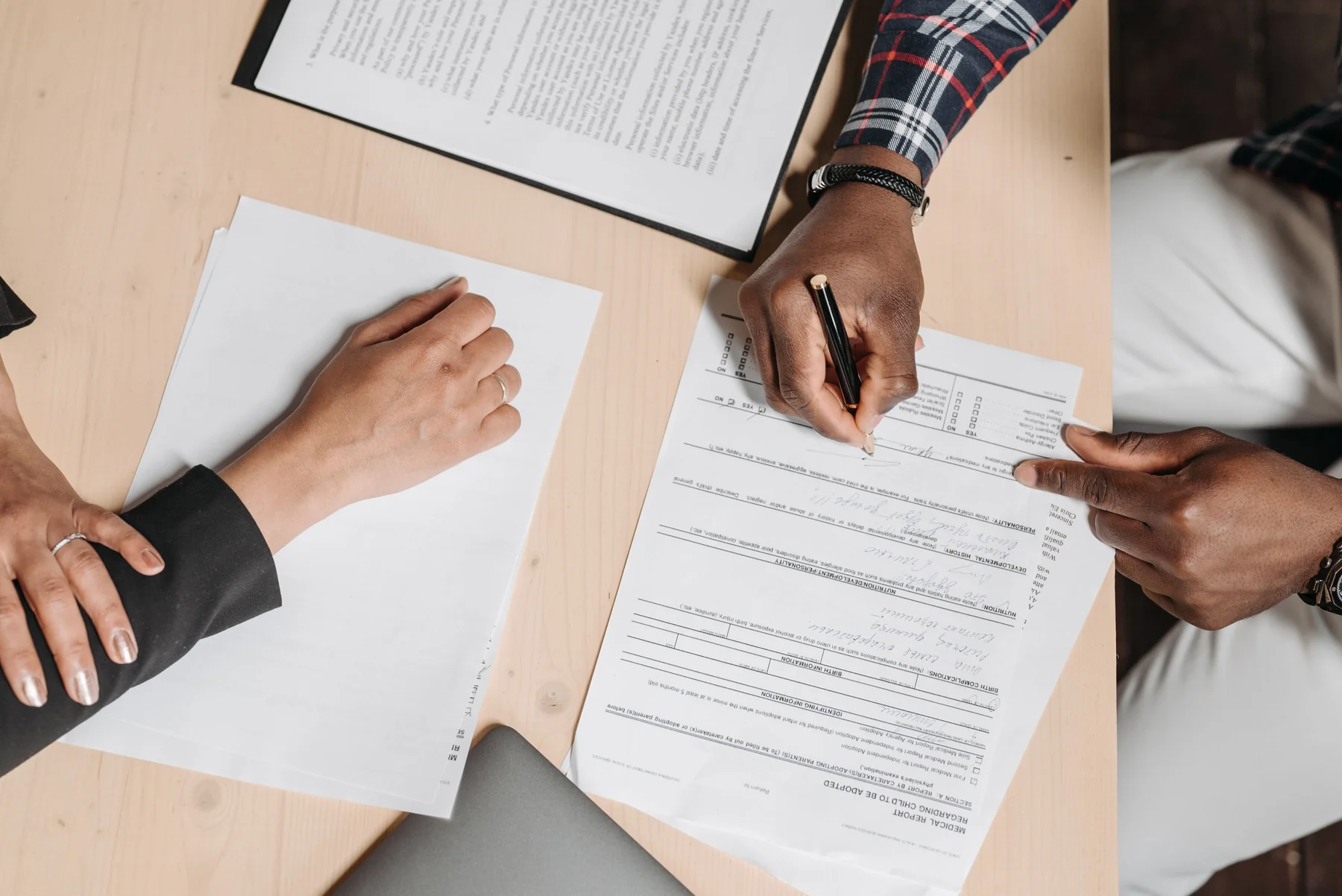 An overhead view of paperwork being reviewed and signed