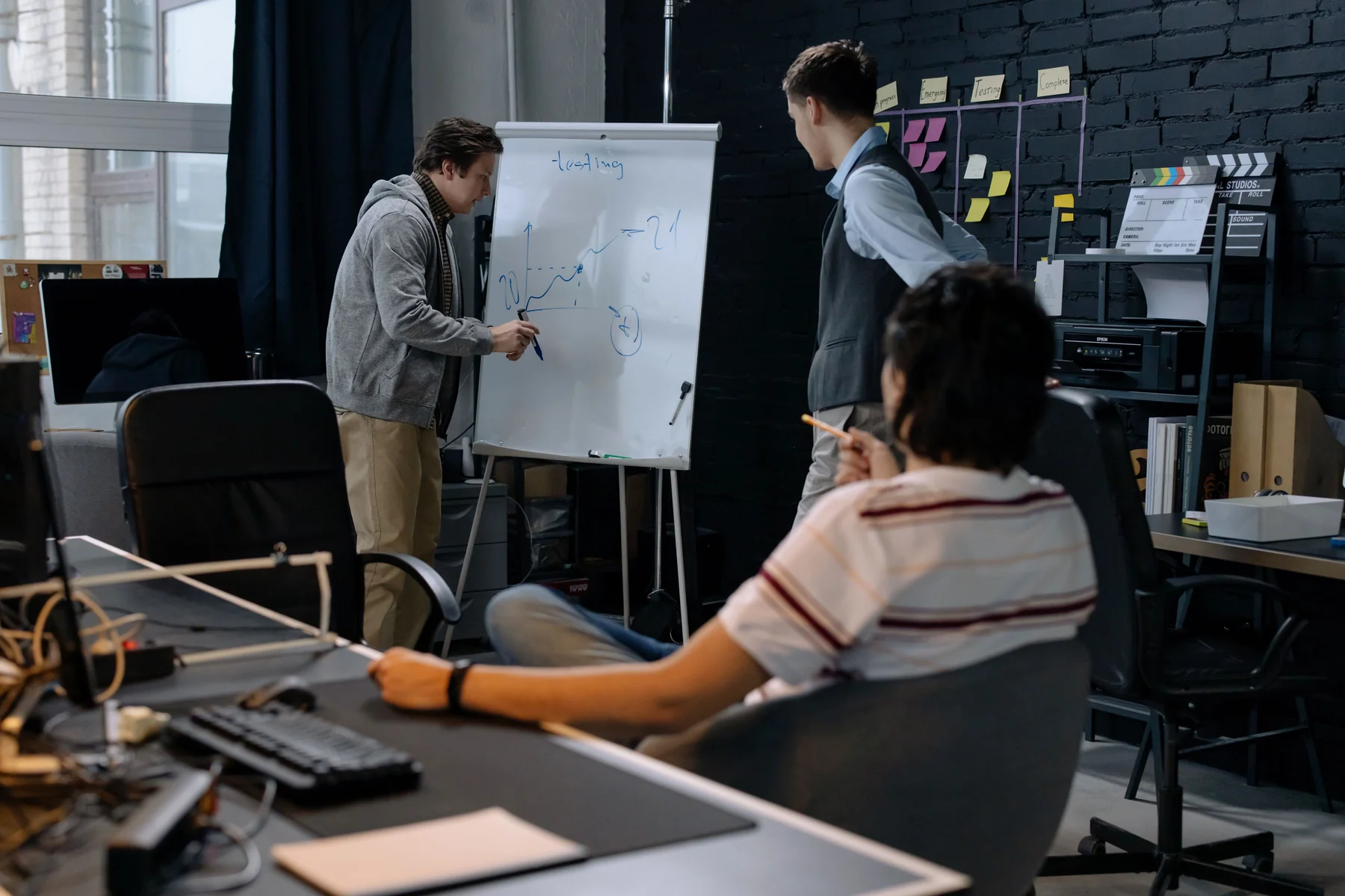Colleagues discussing a flip chart in a working studio