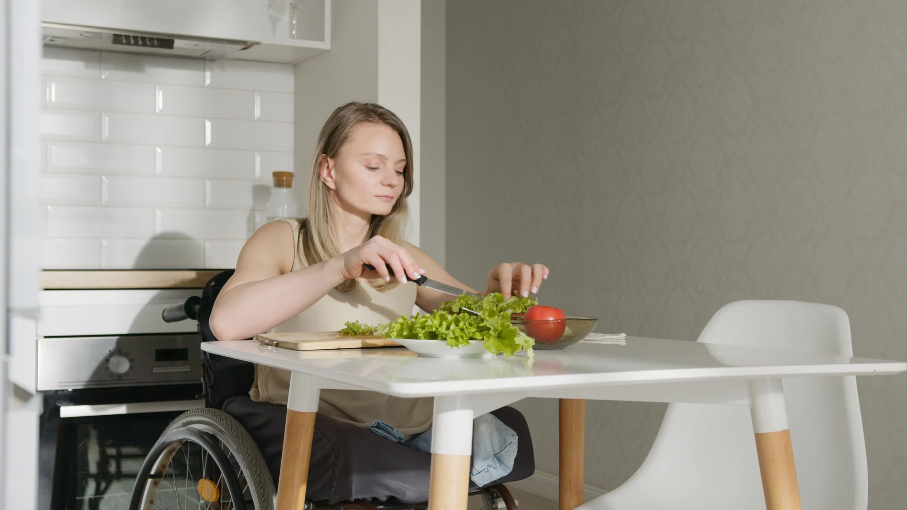 A wheelchair user preparing vegetables in a home kitchen