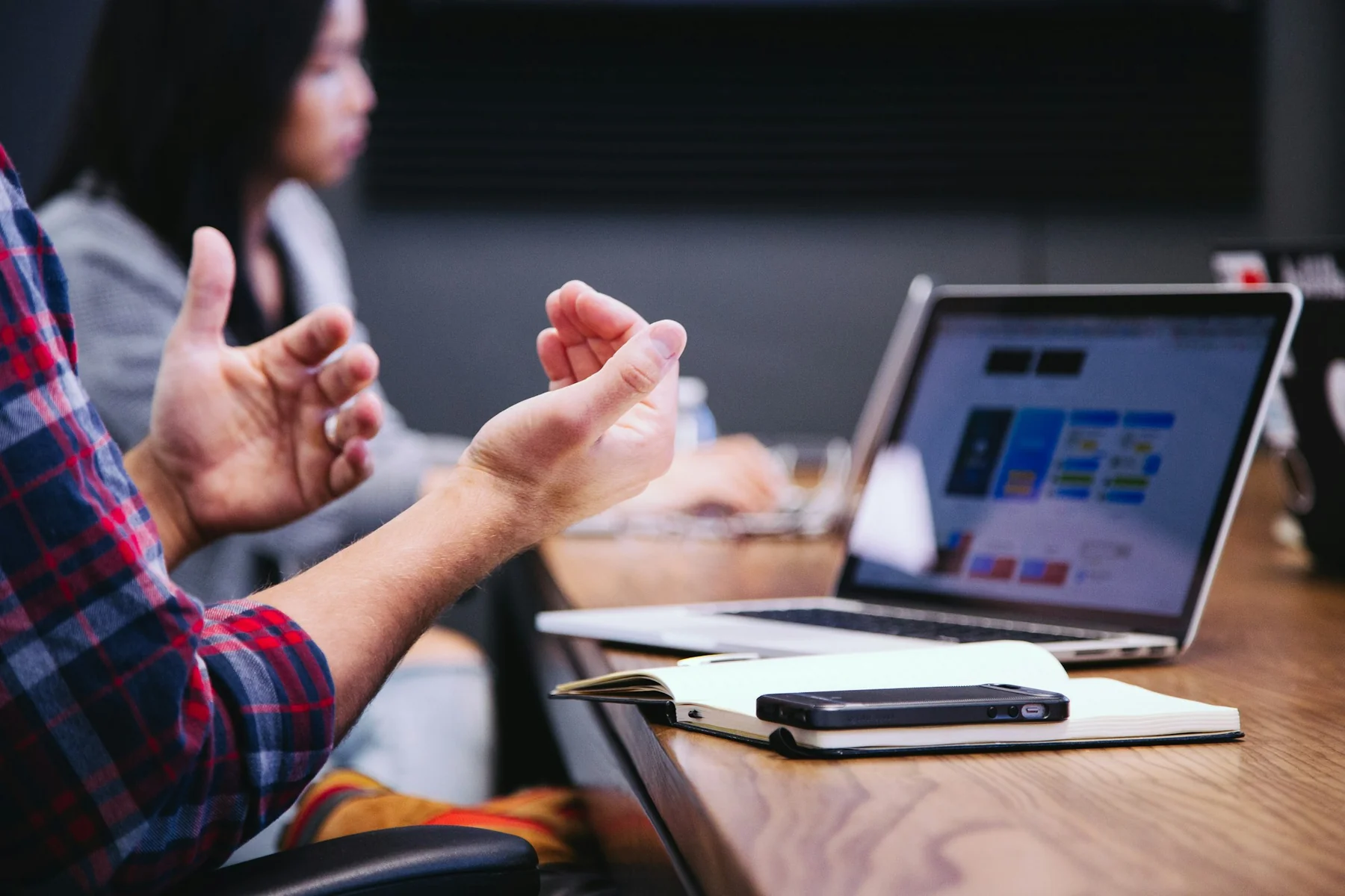 Gesturing hands, a notebook and a laptop during a conversation