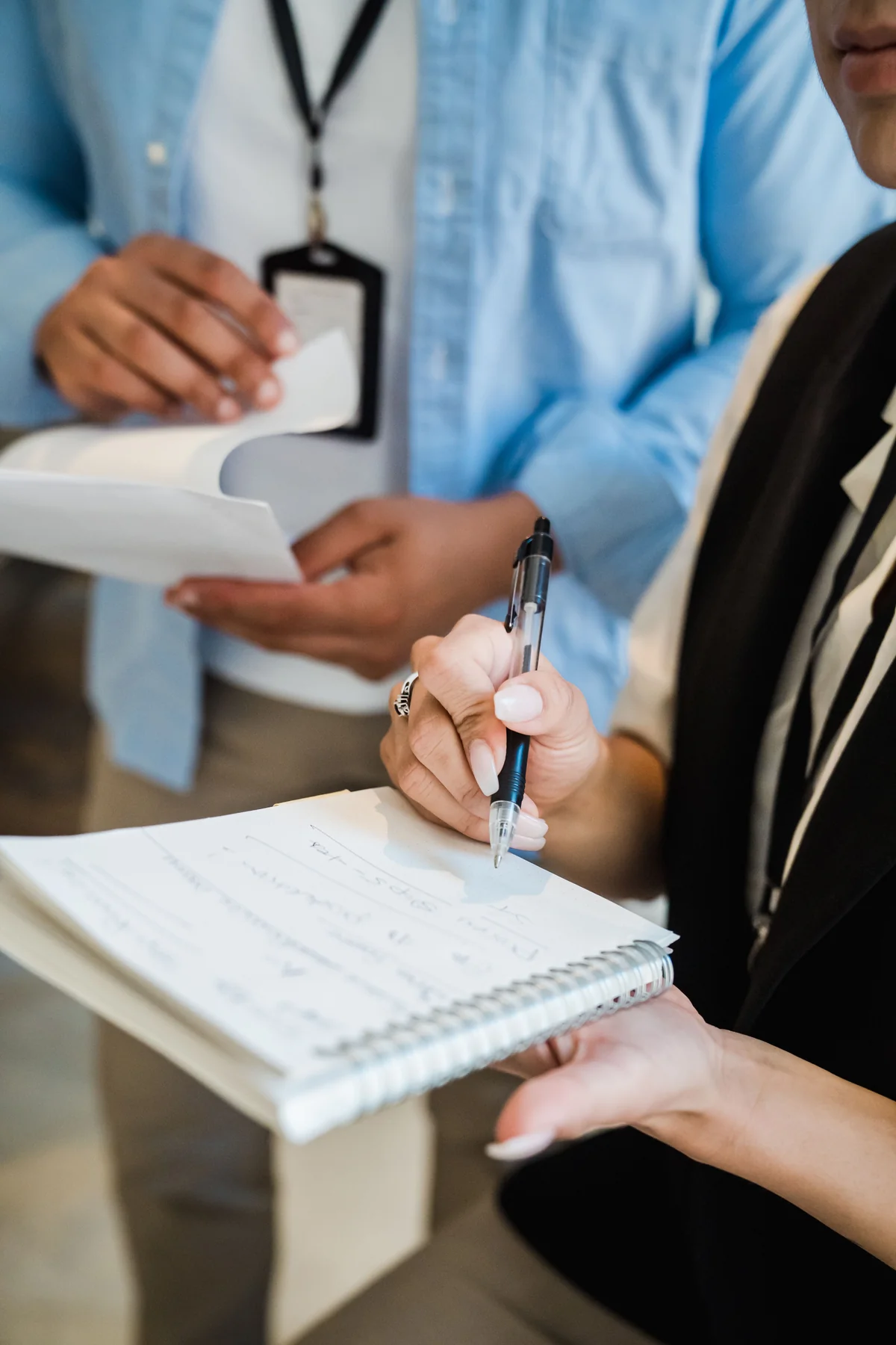 Hands holding notebooks and taking notes during a discussion